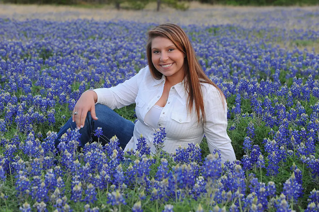 Senior girl sitting in a field of Texas bluebonnets