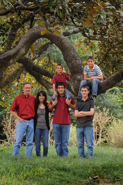 Family of six posed under and in a sprawling oak tree
