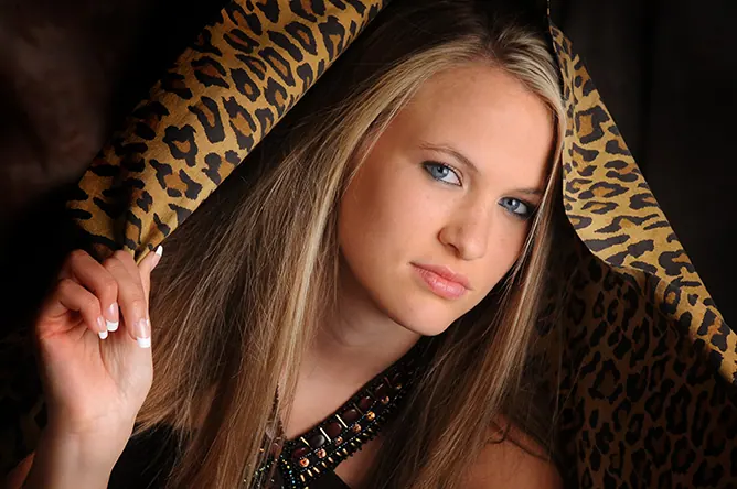 Senior girl framed by a leopard-print scarf in dramatic studio light