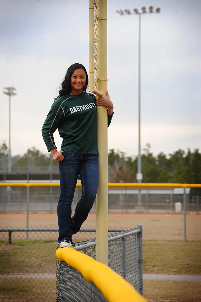 Softball senior leaning on the foul pole of her home field