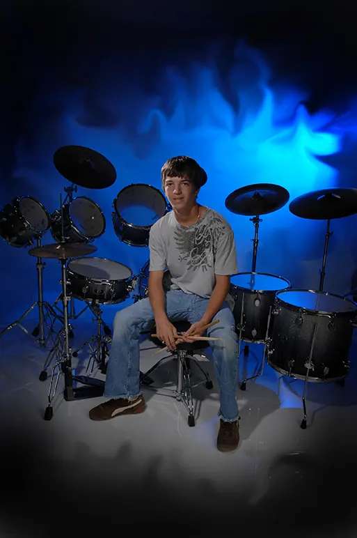Drummer senior at his drum kit lit in electric blue
