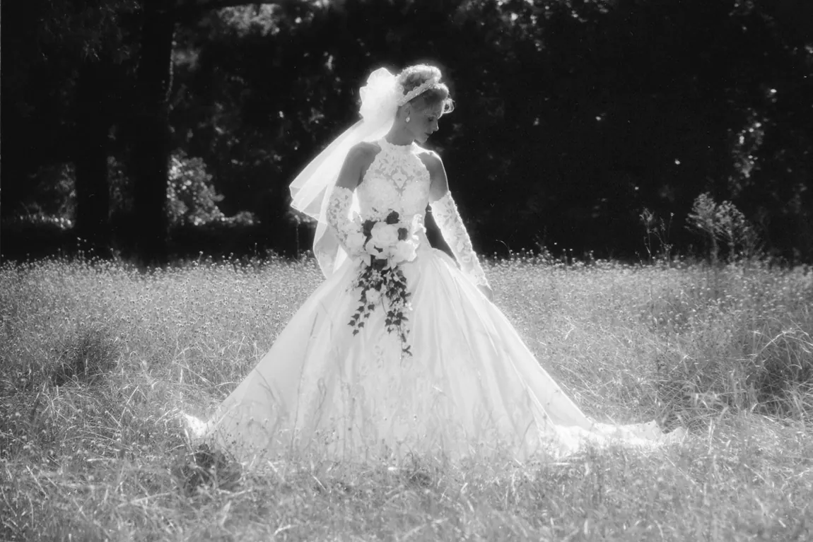 Black-and-white bride with her bouquet in a sunlit meadow