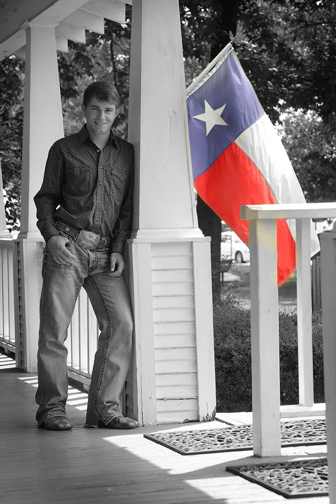 Black-and-white senior on a porch with a color Texas flag