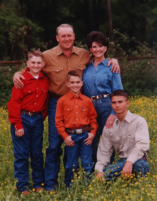 Family in matching red and orange western shirts in a wildflower field