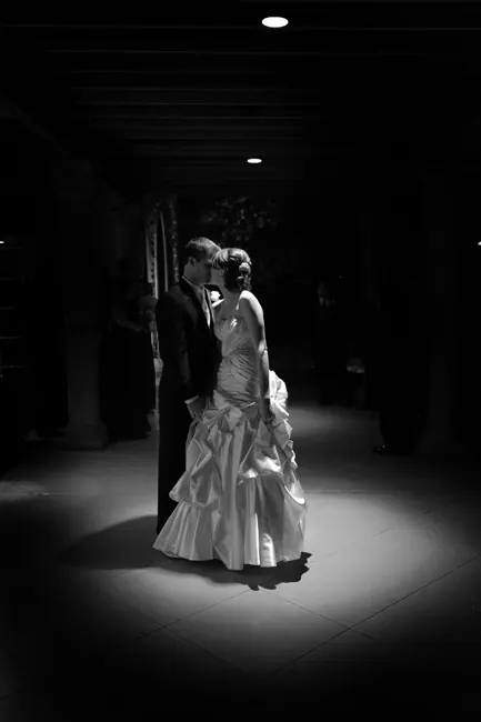Black-and-white bride and groom in a spotlight at night