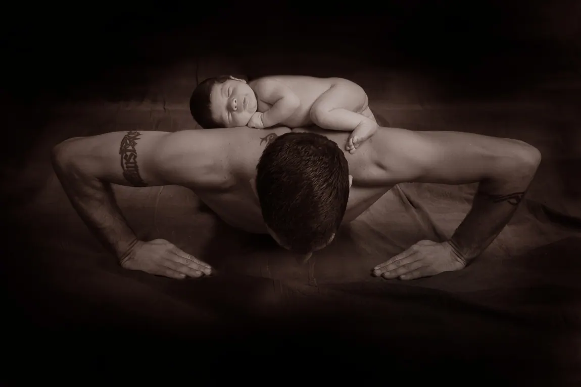 Newborn sleeping on his father's back while dad does a push-up
