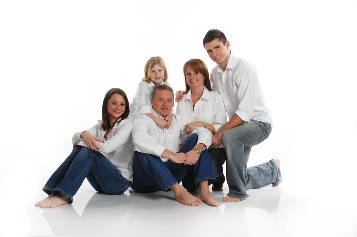 Family of five in white shirts and jeans on a white studio background