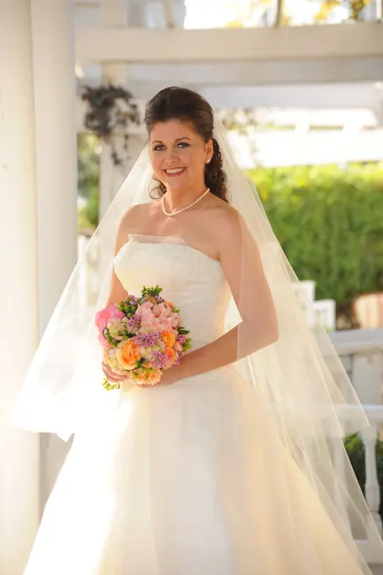 Smiling bride with a colorful bouquet on a white porch