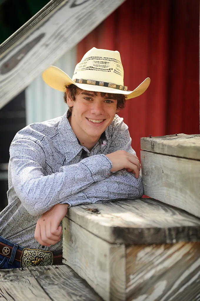 Senior in a straw cowboy hat leaning on weathered wooden steps