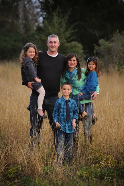 Father with his four children standing in tall golden grass