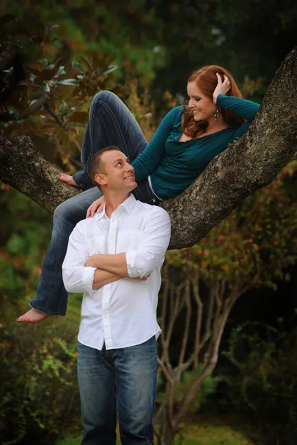 Engaged couple playing in a large oak tree