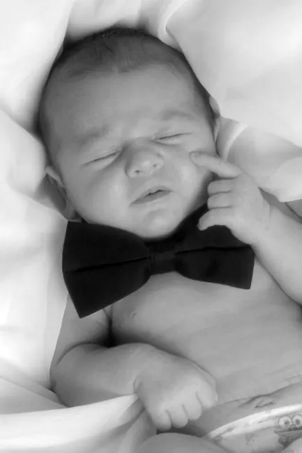 Black-and-white sleeping newborn wearing a black bow tie