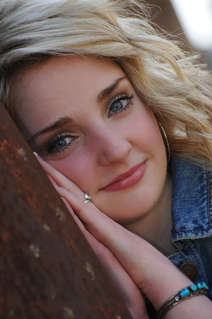Close-up of a blonde senior girl resting her cheek on her hands
