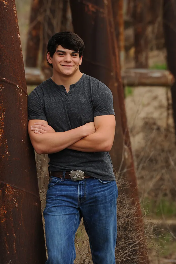Senior boy with crossed arms leaning on a rusty steel beam