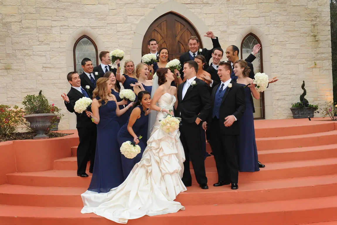 Wedding party cheering on the steps of a stone chapel