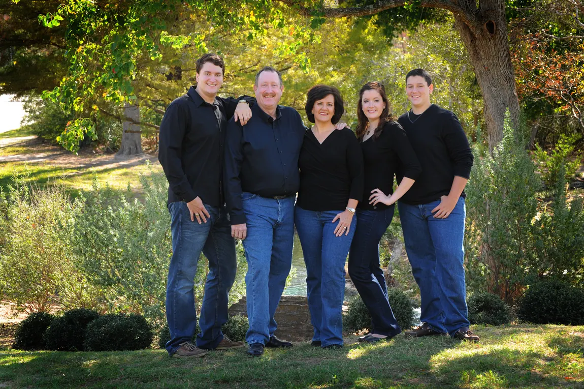 Family of five in coordinated navy standing on a garden lawn