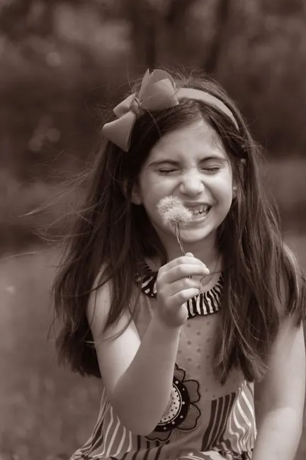 Sepia portrait of a little girl blowing a dandelion