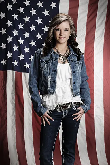 Senior girl in a denim jacket in front of an American flag