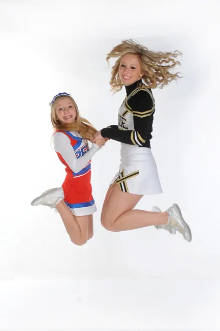 Cheerleader sisters jumping in midair on a white background