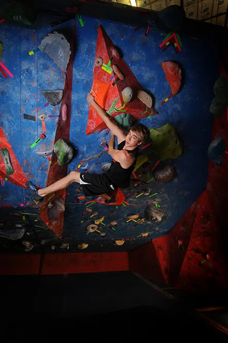 Overhead view of a senior climbing a colorful indoor bouldering wall