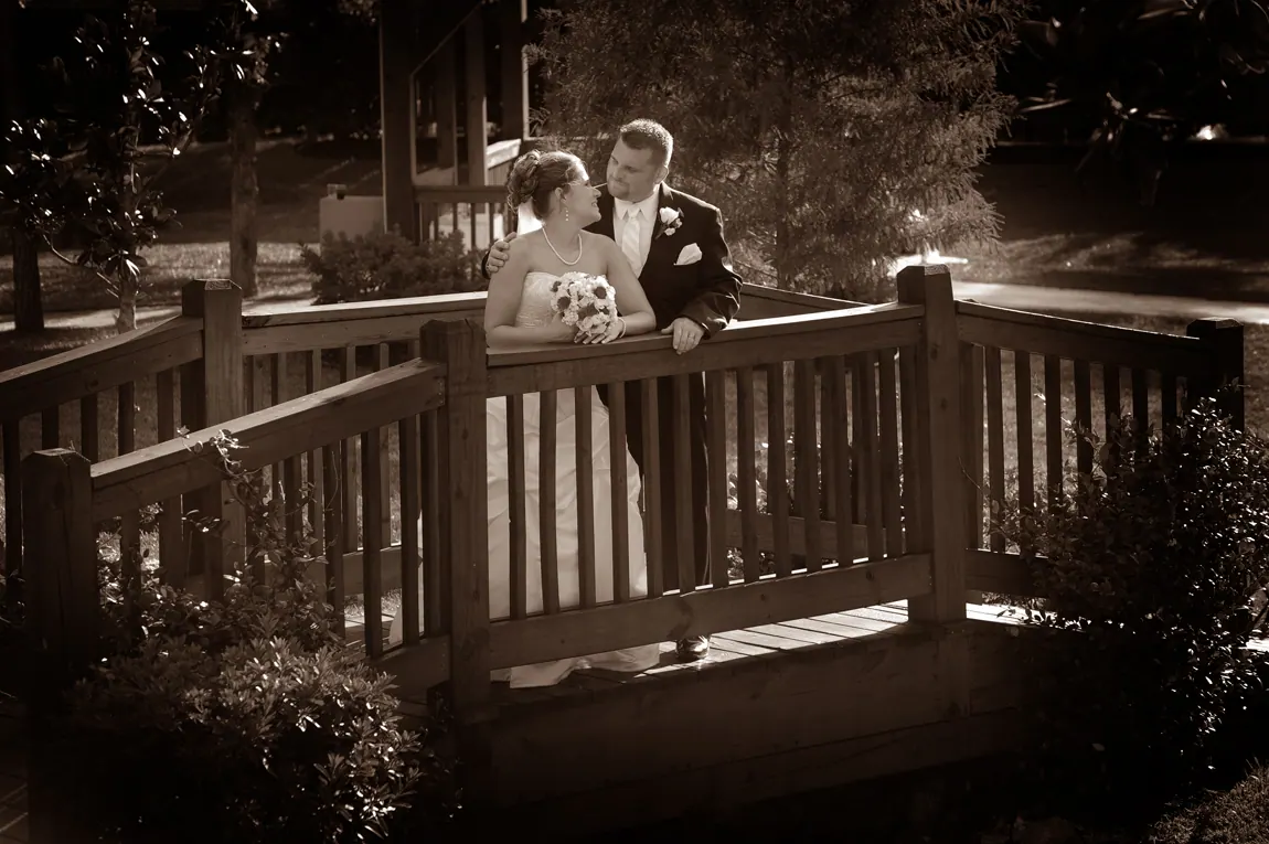 Sepia portrait of a bride and groom on a wooden bridge